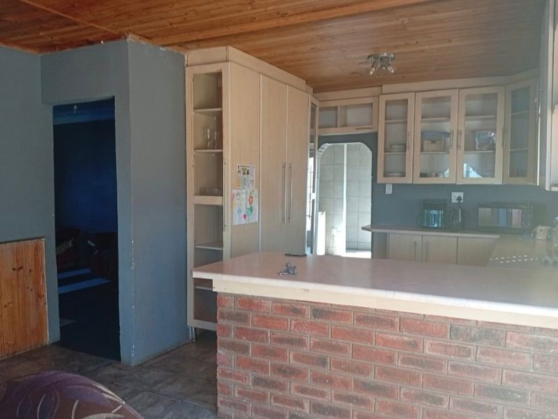 A functional kitchen featuring built-in cabinetry, a brick breakfast bar, and a timber-clad ceiling, offering a dated aesthetic with potential for modernization.