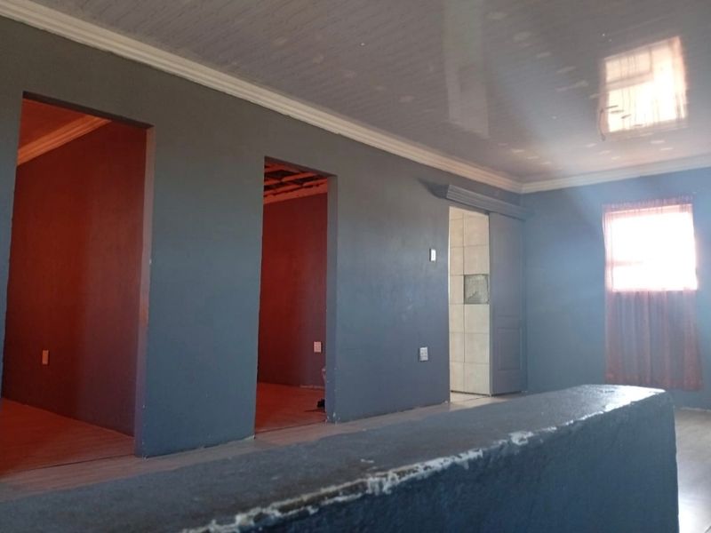 An empty living area featuring dark grey walls, glossy ceiling panels, and multiple doorways leading to adjacent rooms.