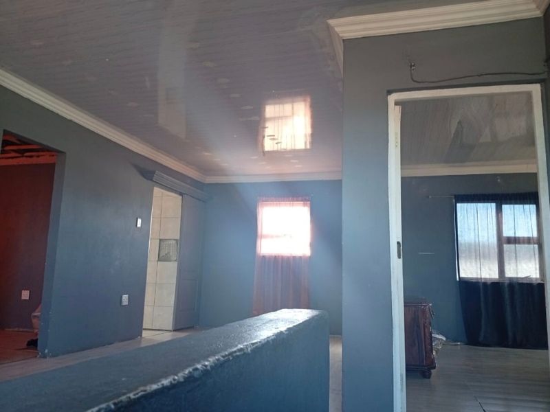 An empty living area featuring a glossy ceiling, crown molding, and dark grey walls, offering a blank canvas for interior design updates.