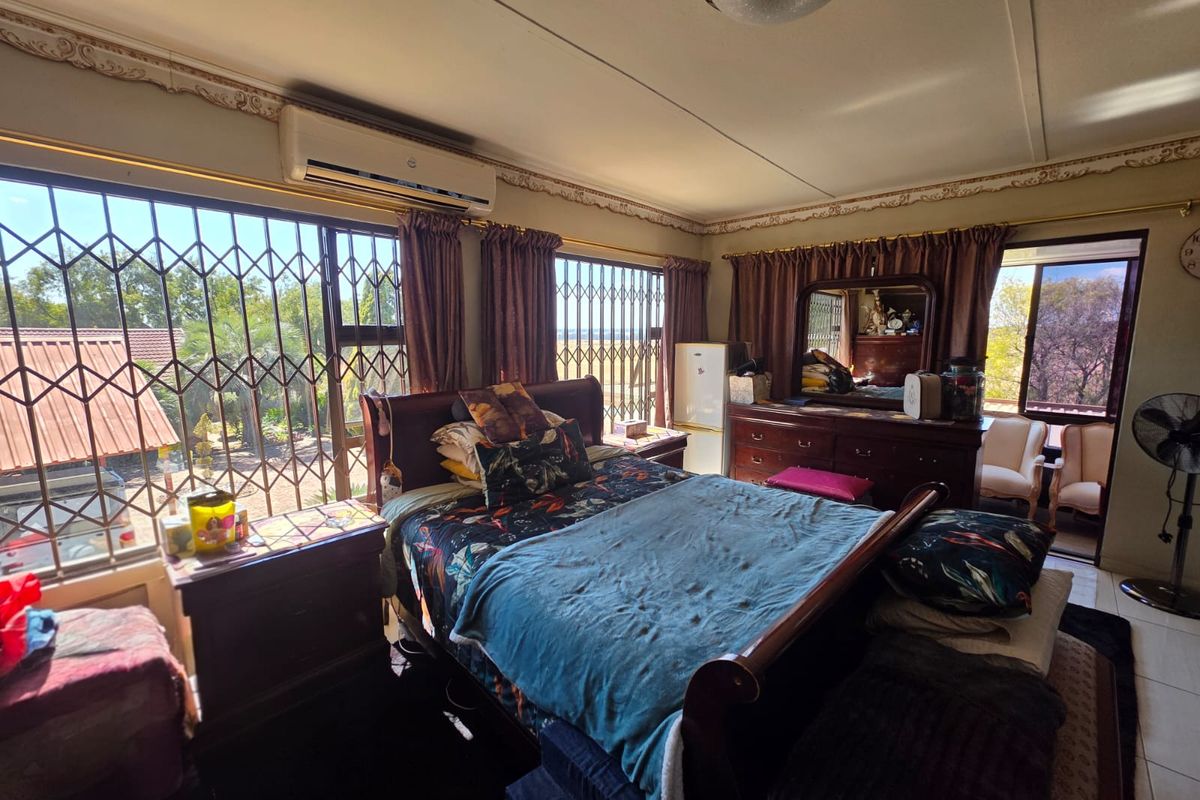 Spacious bedroom featuring large windows with security gates, split-system air conditioning, and direct access to an outdoor area.