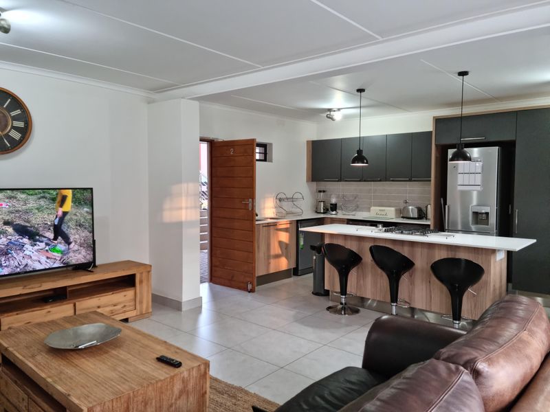 Modern open-plan living area featuring a contemporary kitchen with a central island, gas hob, and sleek cabinetry, seamlessly flowing into the lounge space.