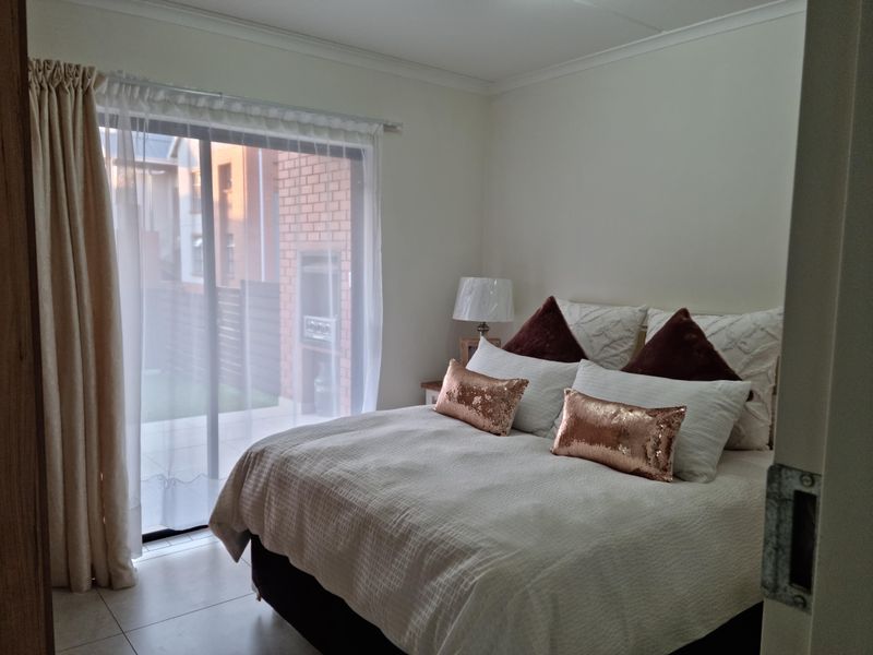 A well-lit bedroom featuring tiled flooring and a large sliding glass door providing direct access to the outdoor patio area.