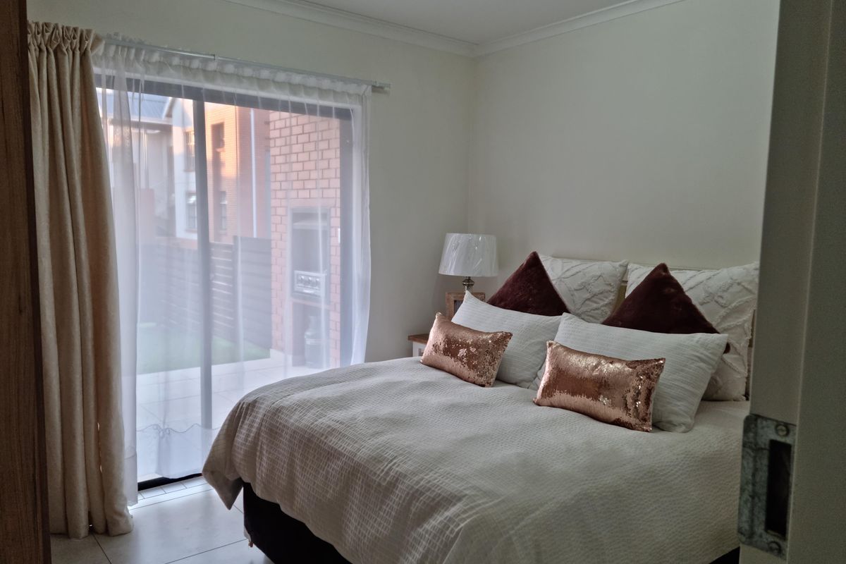 A well-lit bedroom featuring tiled flooring and a large sliding glass door providing direct access to the outdoor patio area.