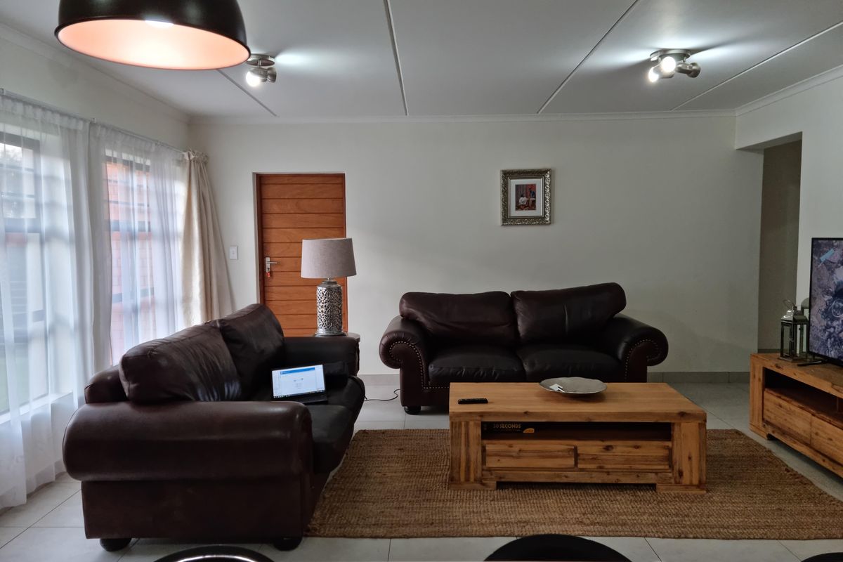 A well-maintained living room featuring tiled flooring, neutral walls, and natural light from large windows, creating a comfortable and inviting space.