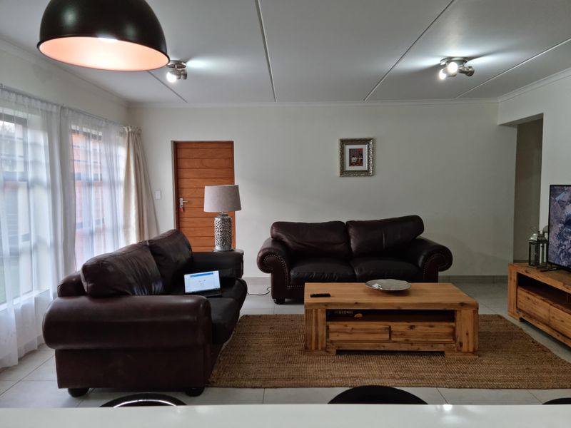 A well-maintained living room featuring tiled flooring, neutral walls, and natural light from large windows, creating a comfortable and inviting space.