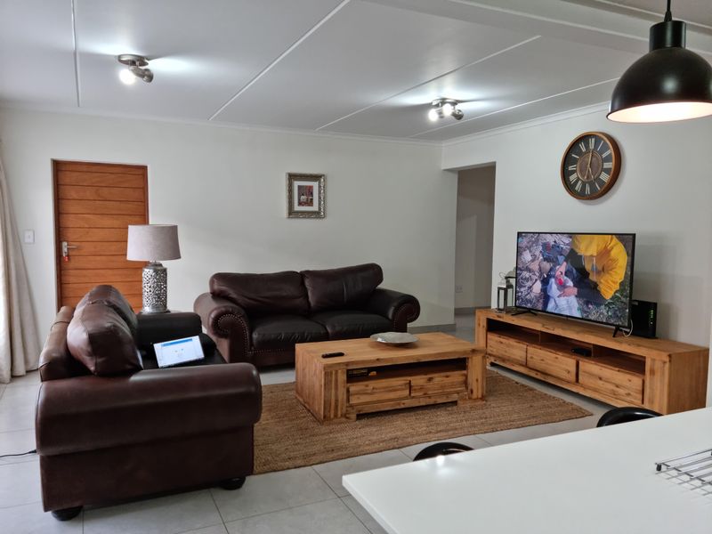 A well-maintained living room featuring neutral tiled flooring, clean white walls, and modern flush-mount ceiling lighting.