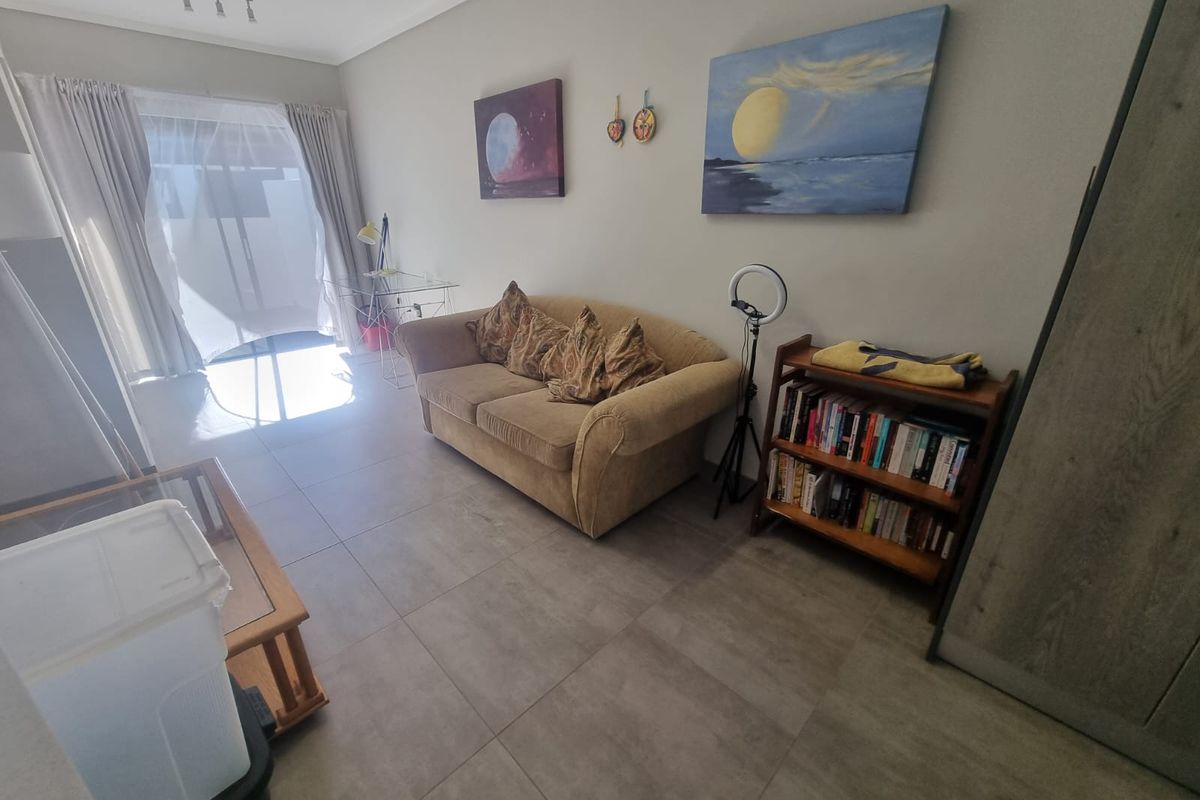 A living room area featuring large format floor tiles and sliding glass doors leading to an outdoor space.