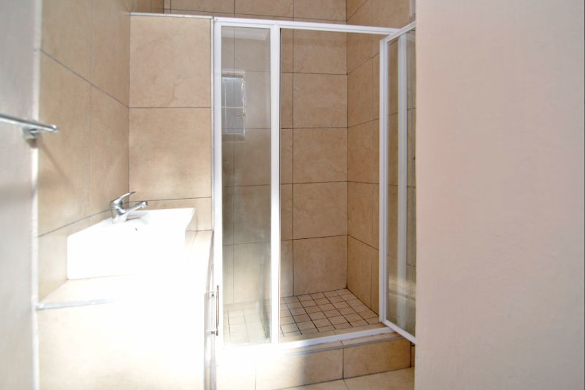 A functional bathroom featuring a tiled shower enclosure with a glass door and a built-in vanity basin.