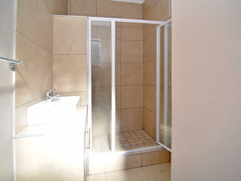 A functional bathroom featuring a tiled shower enclosure with a glass door and a built-in vanity basin.