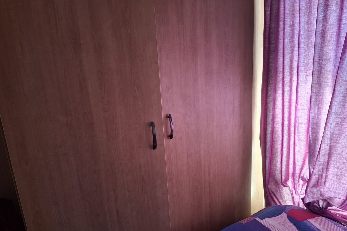 A bedroom featuring built-in wooden cabinetry with dark handles, providing integrated storage space.