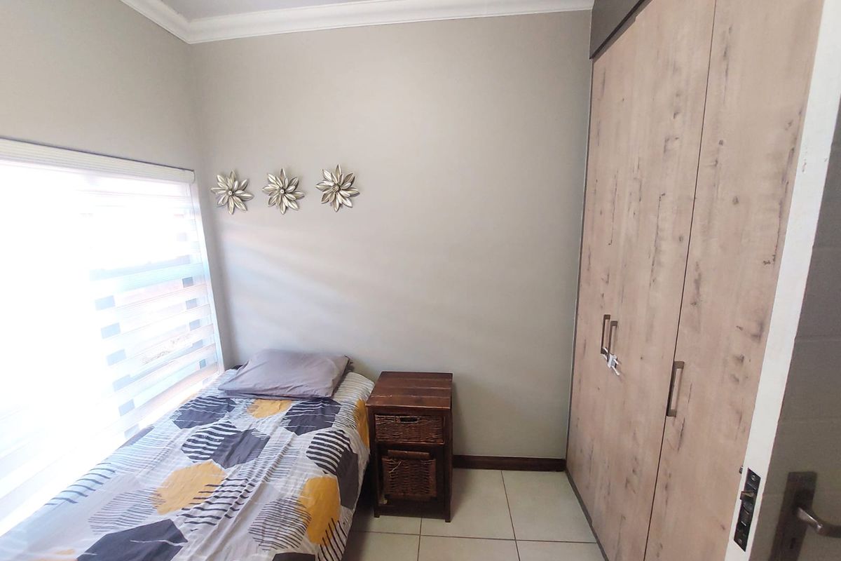 A compact bedroom featuring built-in wooden cabinetry and tiled flooring, offering a functional and well-maintained living space.