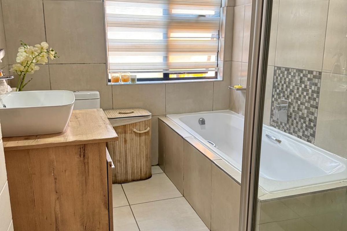 A modern bathroom featuring a built-in bathtub, a separate glass-enclosed shower, and a wooden vanity with a vessel sink.