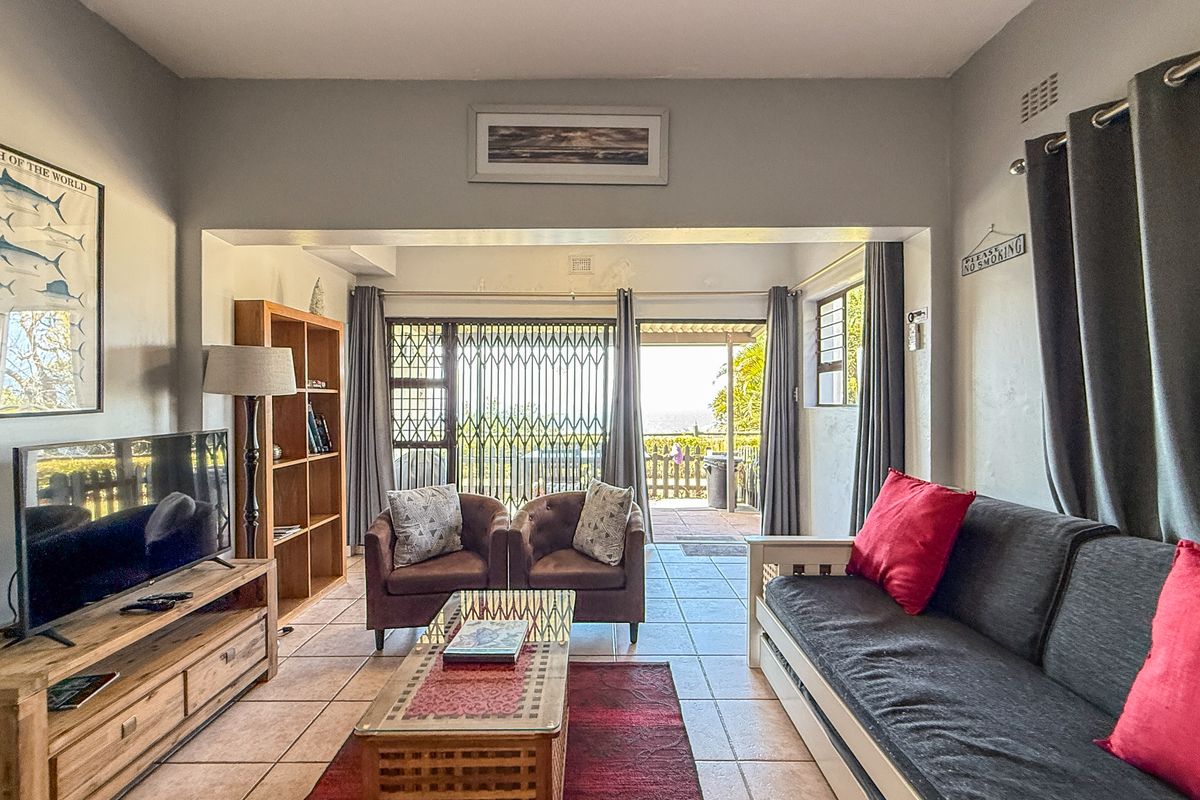 A comfortable living room featuring tiled flooring, built-in shelving, and large sliding doors that open onto an outdoor patio area.