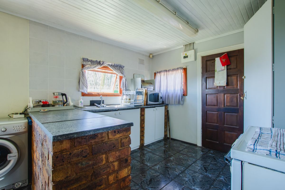 A functional kitchen featuring brick-base cabinetry, tiled splashbacks, and integrated laundry space with direct access to an exterior door.