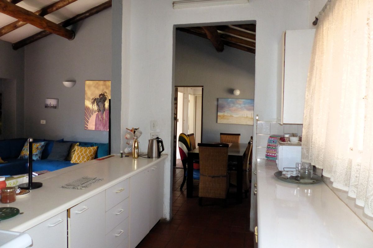A functional kitchen area featuring white cabinetry and tiled flooring, with an open-plan layout connecting to the adjacent living and dining spaces.