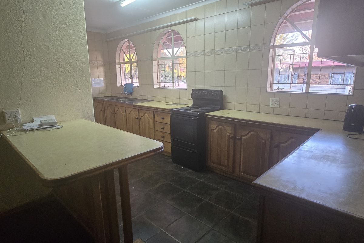A dated kitchen featuring wooden cabinetry, laminate countertops, tiled walls, and a freestanding stove, offering a functional layout with potential for modernization.
