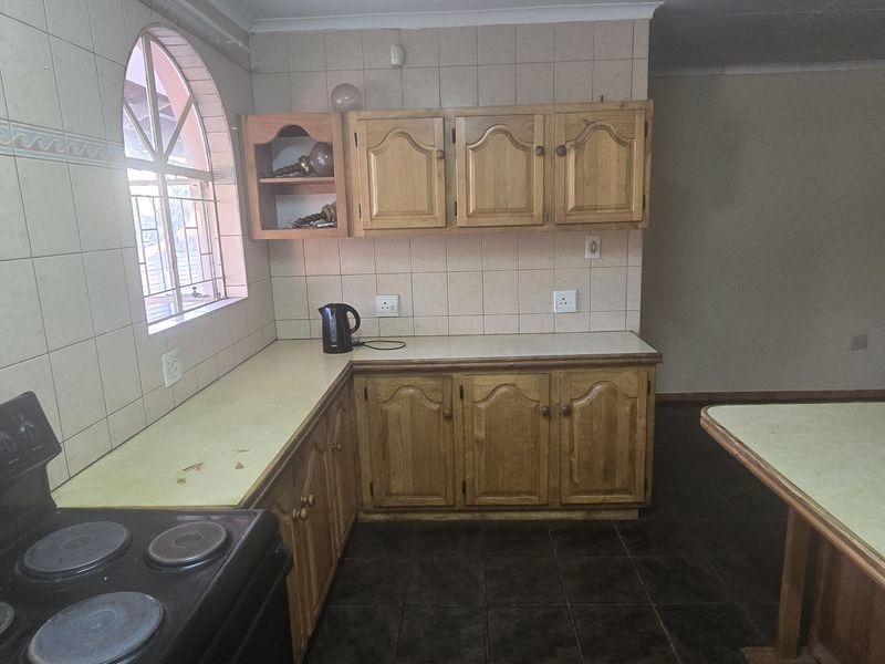 A functional kitchen featuring wooden cabinetry, tiled splashbacks, a built-in stove, and a breakfast counter, offering a classic layout with potential for modernization.