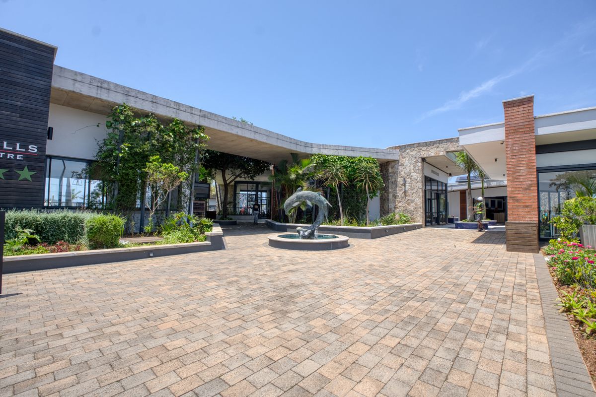A well-maintained outdoor courtyard area featuring paved flooring, a central fountain, and modern architectural elements with integrated landscaping.