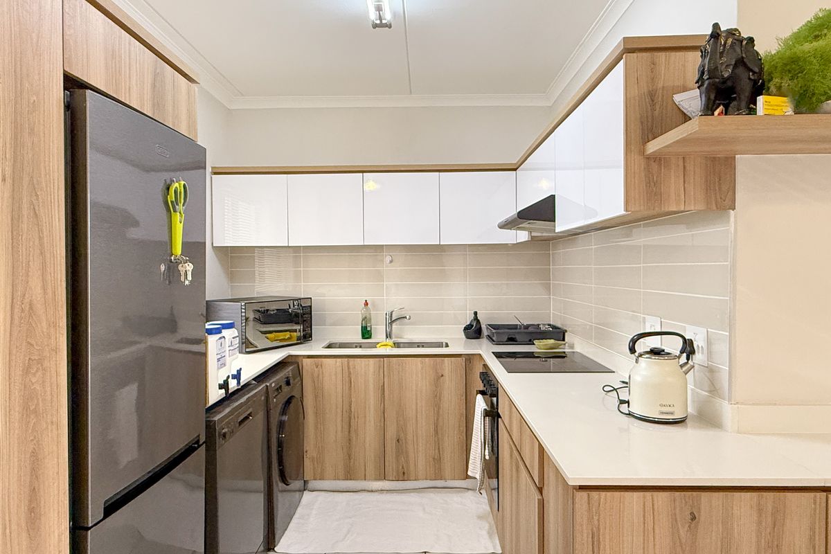 Modern kitchen featuring wood-grain cabinetry, white high-gloss upper cabinets, stone countertops, integrated hob, and tiled backsplash.