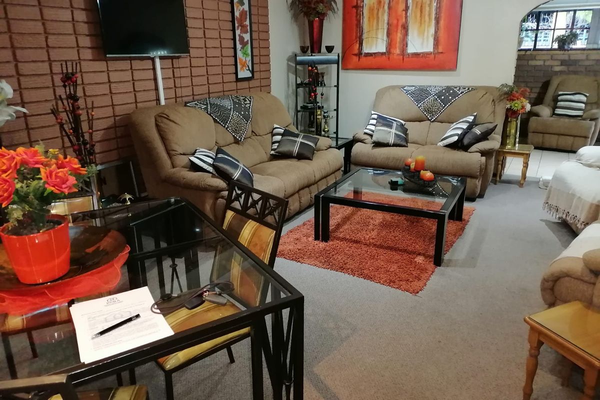 A living room featuring a prominent exposed brick feature wall and carpeted flooring, providing a cozy and traditional living space.