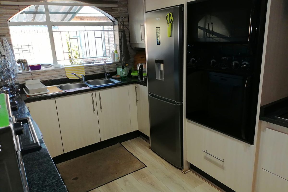 A functional kitchen featuring built-in cabinetry, dark granite countertops, a double stainless steel sink, and integrated oven and microwave units.
