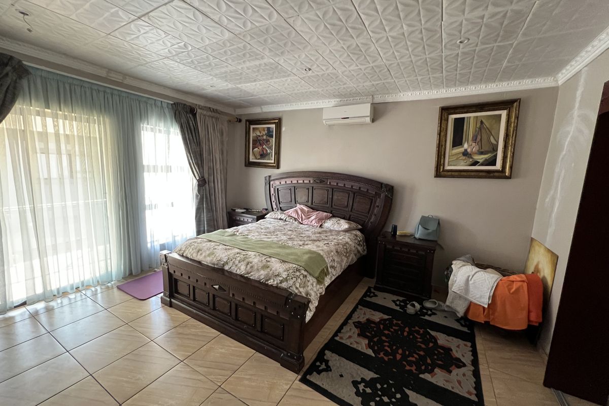 Spacious bedroom featuring tiled flooring, a wall-mounted air conditioning unit, and sliding glass doors providing access to the exterior.