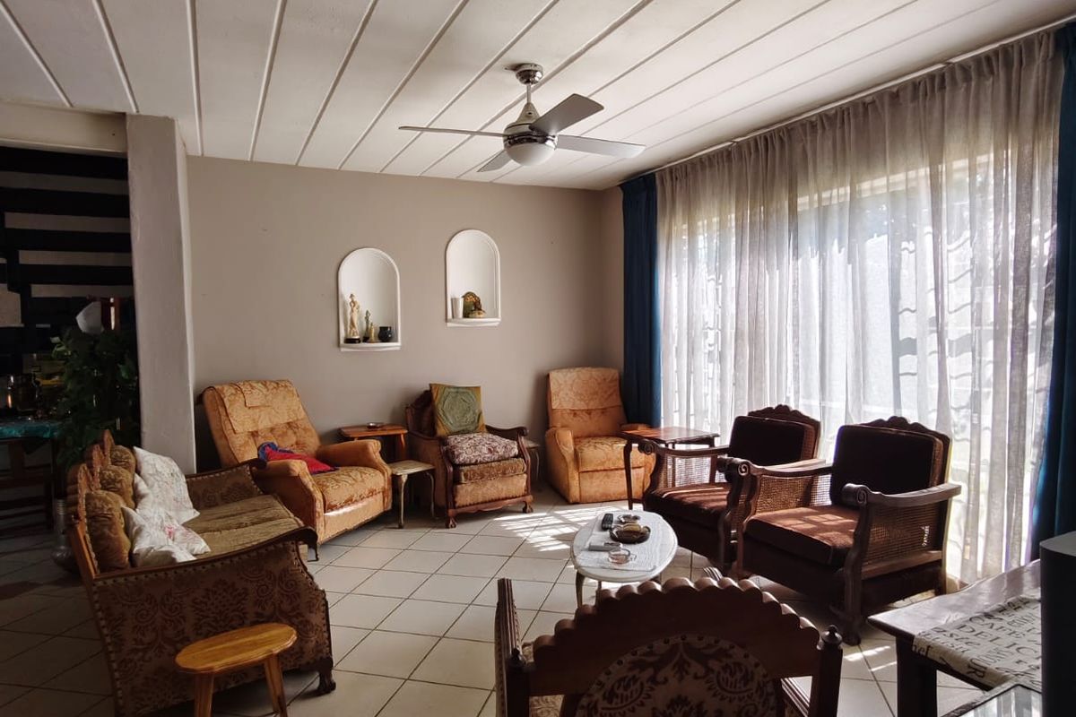Spacious living room featuring tiled flooring, a ceiling fan, and two built-in arched wall niches, offering a bright and functional living space.