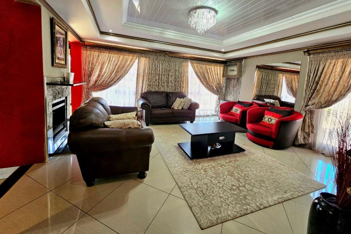 Spacious living room featuring tiled flooring, a built-in fireplace with stone cladding, and a decorative tray ceiling with recessed lighting.