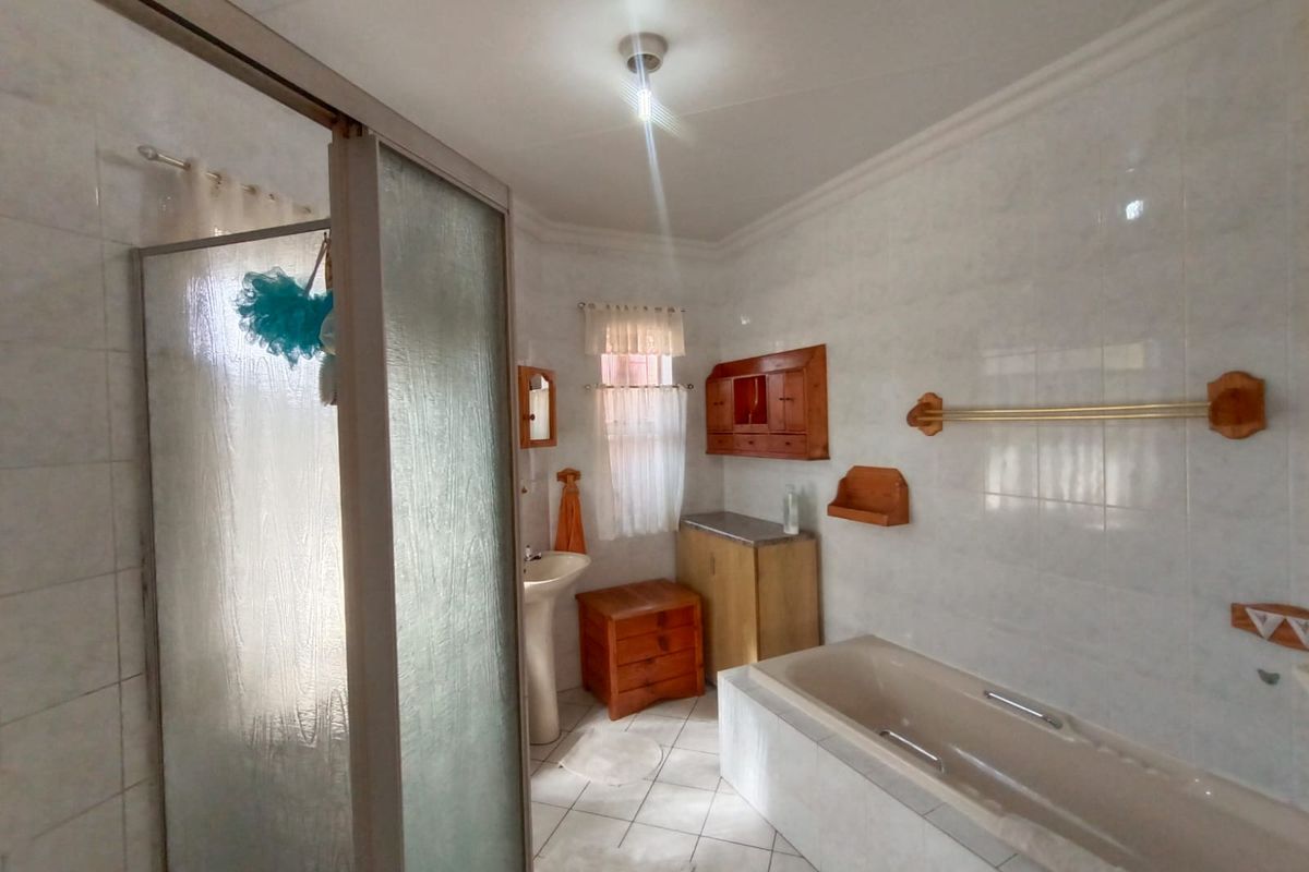 A functional bathroom featuring a built-in bathtub, a separate shower enclosure, a pedestal sink, and tiled wall finishes.