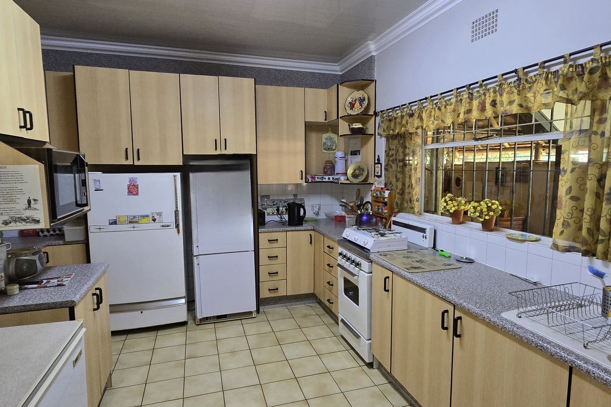 A functional kitchen featuring light wood-finish cabinetry, laminate countertops, a built-in stove, and tiled flooring with a window overlooking the exterior.