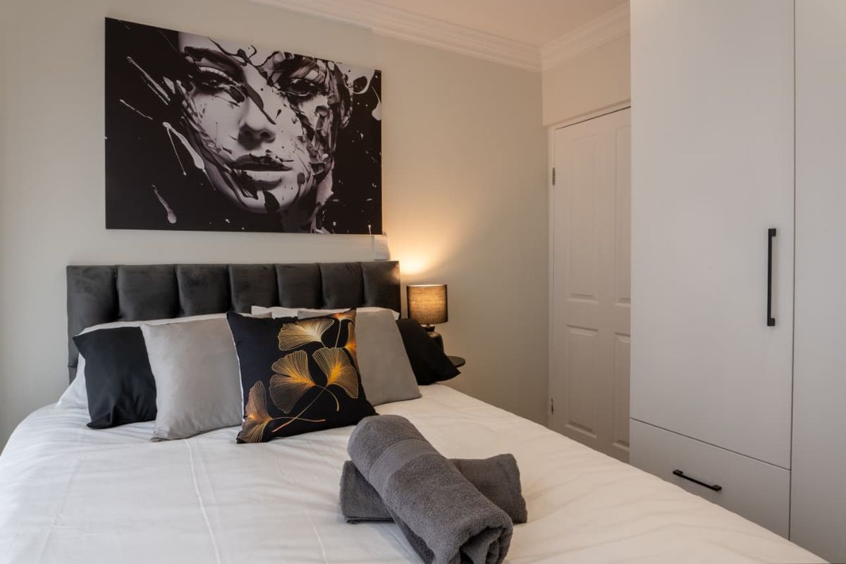 A well-maintained bedroom featuring built-in cabinetry, crown molding, and a neutral color palette, providing a clean and functional living space.