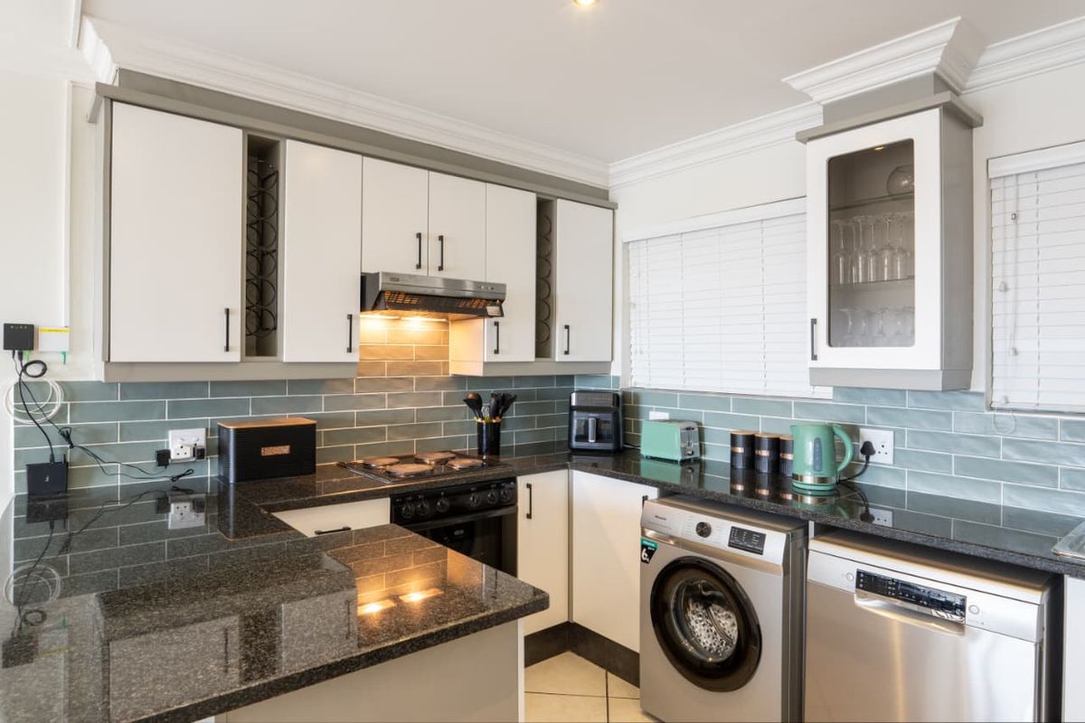 Modern kitchen featuring granite countertops, subway tile backsplash, built-in oven with extractor fan, and integrated space for laundry and dishwasher appliances.
