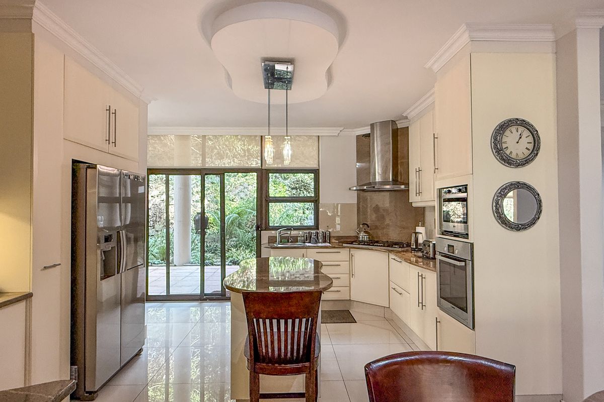 Modern kitchen featuring granite countertops, built-in stainless steel appliances, a central island, and direct access to an outdoor patio area.