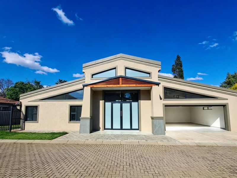 Modern front facade featuring a double garage, paved driveway, and a striking entrance with timber canopy and large glass double doors.