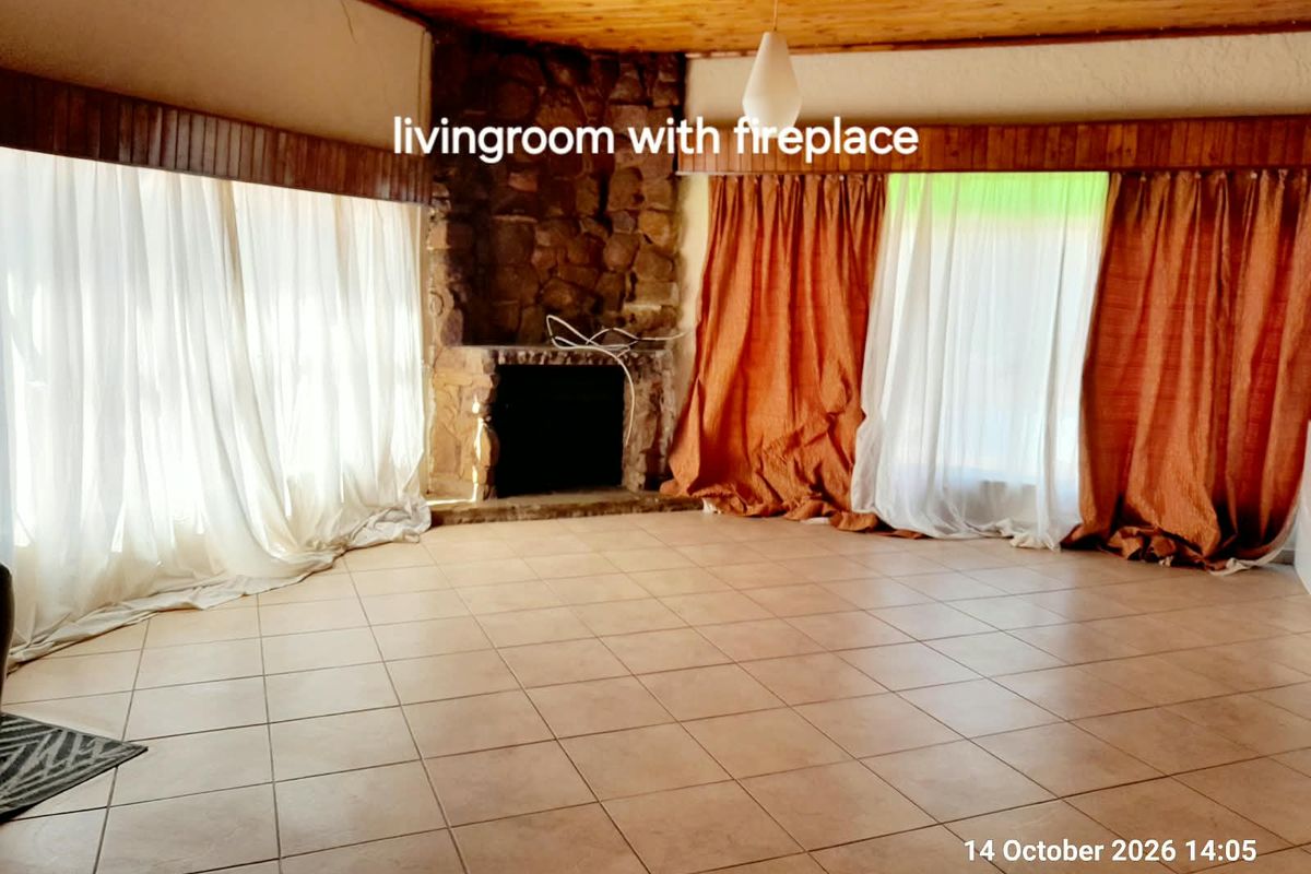 Spacious living room featuring a rustic stone fireplace, tiled flooring, and a timber-clad ceiling, offering a blank canvas for interior design.