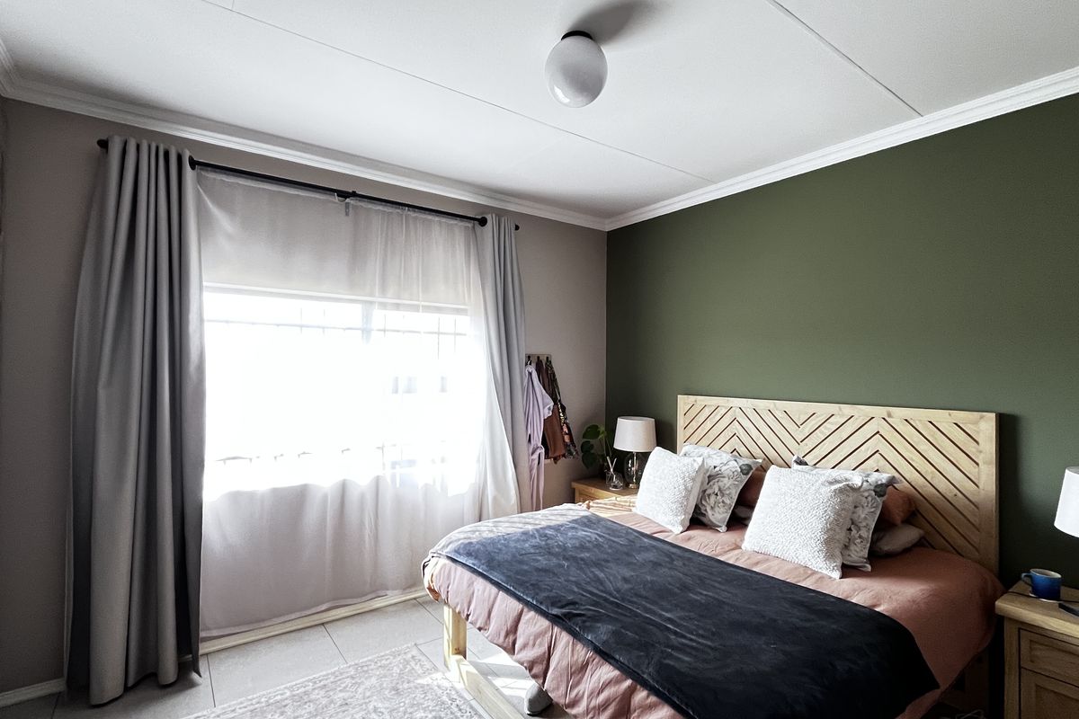A well-maintained bedroom featuring built-in cupboards, tiled flooring, and a feature wall, offering a comfortable and functional living space.