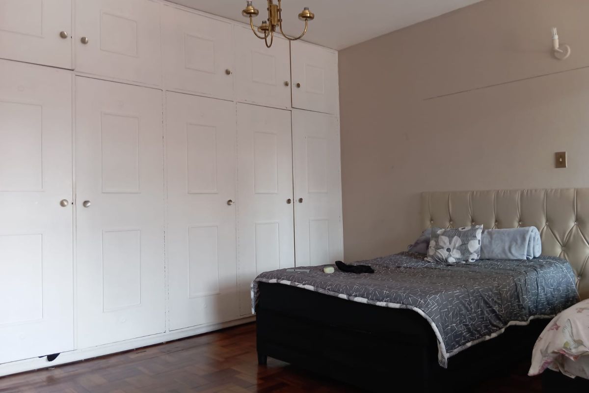 A bedroom featuring extensive floor-to-ceiling built-in cabinetry and traditional parquet wood flooring.