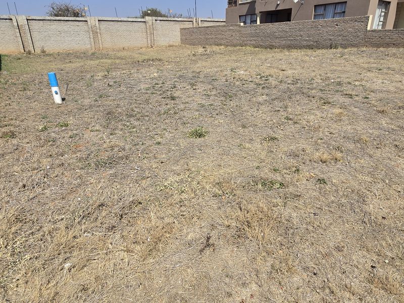 A vacant residential plot featuring perimeter boundary walls and existing utility connection points, ready for development.