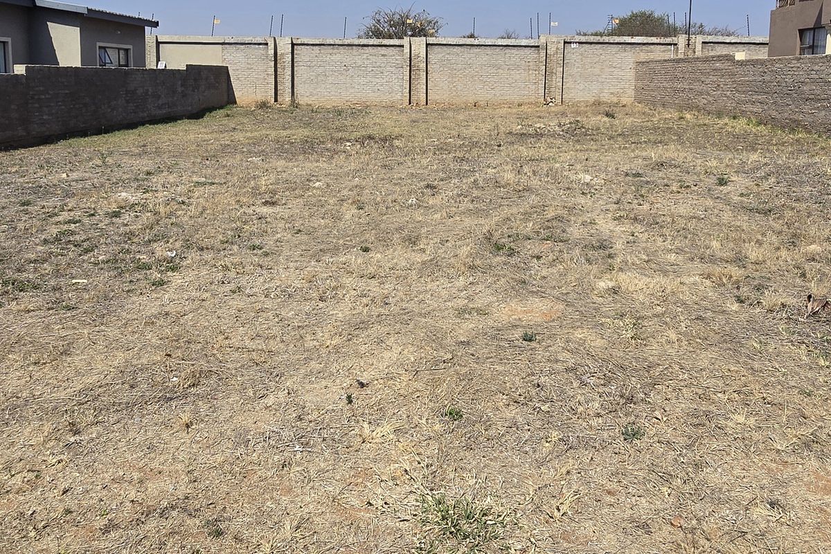 A vacant residential plot enclosed by perimeter brick boundary walls, offering a clear space ready for development.