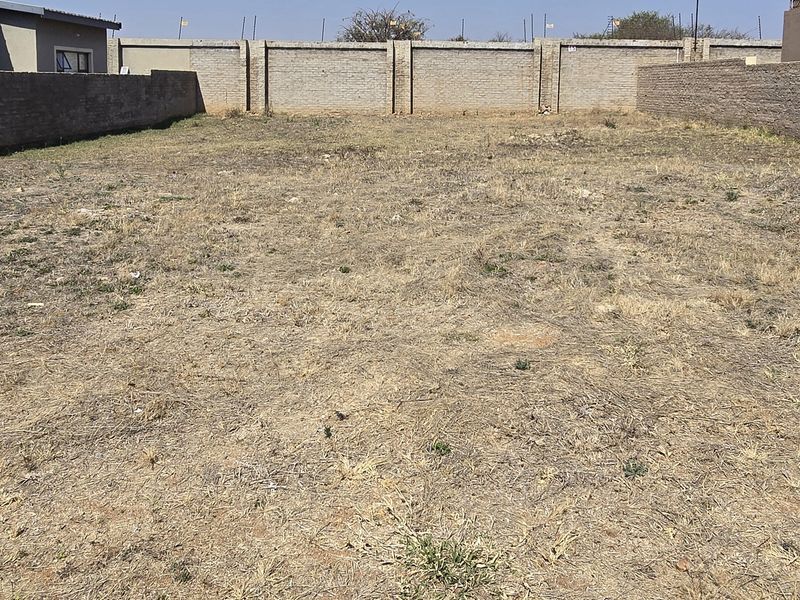A vacant residential plot enclosed by perimeter brick boundary walls, offering a clear space ready for development.