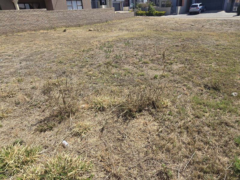 A vacant residential plot featuring perimeter boundary walls, offering a clear space ready for development in an established neighborhood.