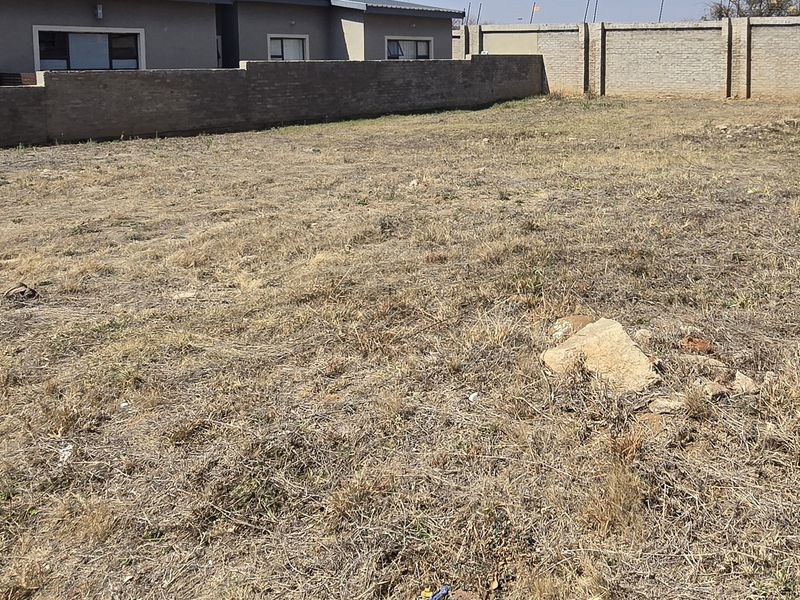 A vacant residential plot featuring perimeter boundary walls, offering a clear and level space ready for future development.