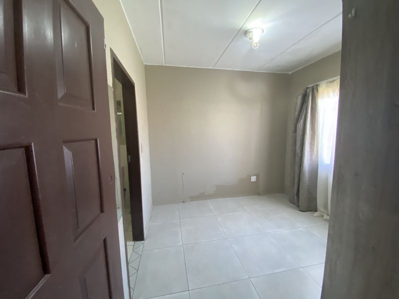 An empty bedroom featuring tiled flooring and neutral wall finishes, ready for personalization or staging.