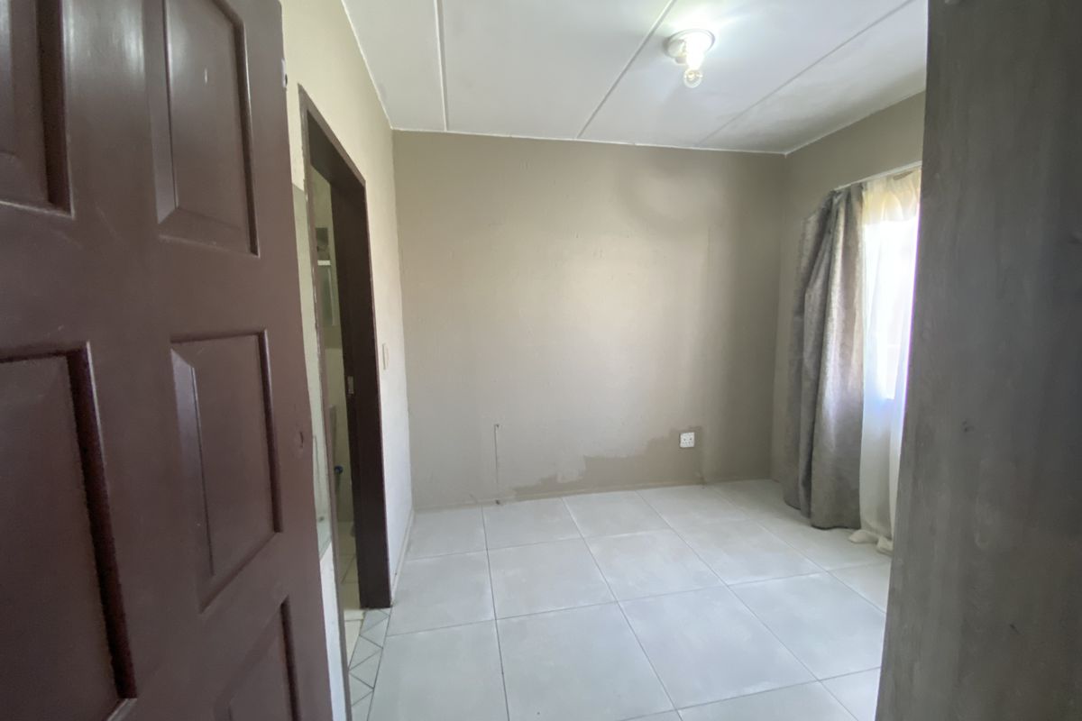 An empty bedroom featuring tiled flooring and neutral wall finishes, ready for personalization or staging.