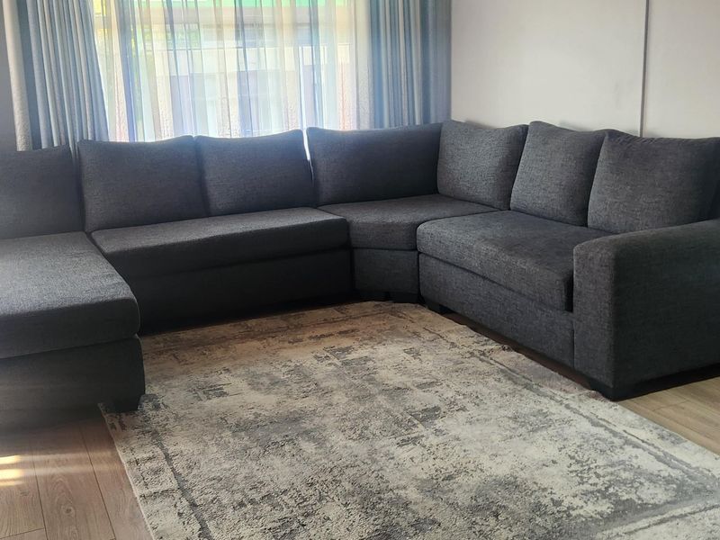 A comfortable living room featuring light-toned laminate flooring, a warm timber-paneled ceiling, and a wall-mounted split-system air conditioning unit.