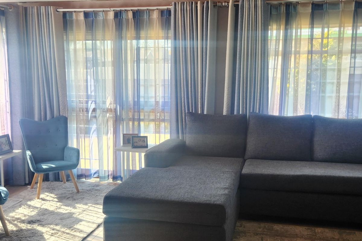 A comfortable living room featuring timber ceilings, laminate flooring, and sliding glass doors that provide natural light and access to the exterior.