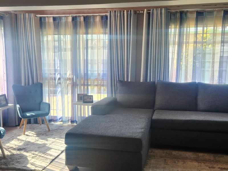 A comfortable living room featuring timber ceilings, laminate flooring, and sliding glass doors that provide natural light and access to the exterior.