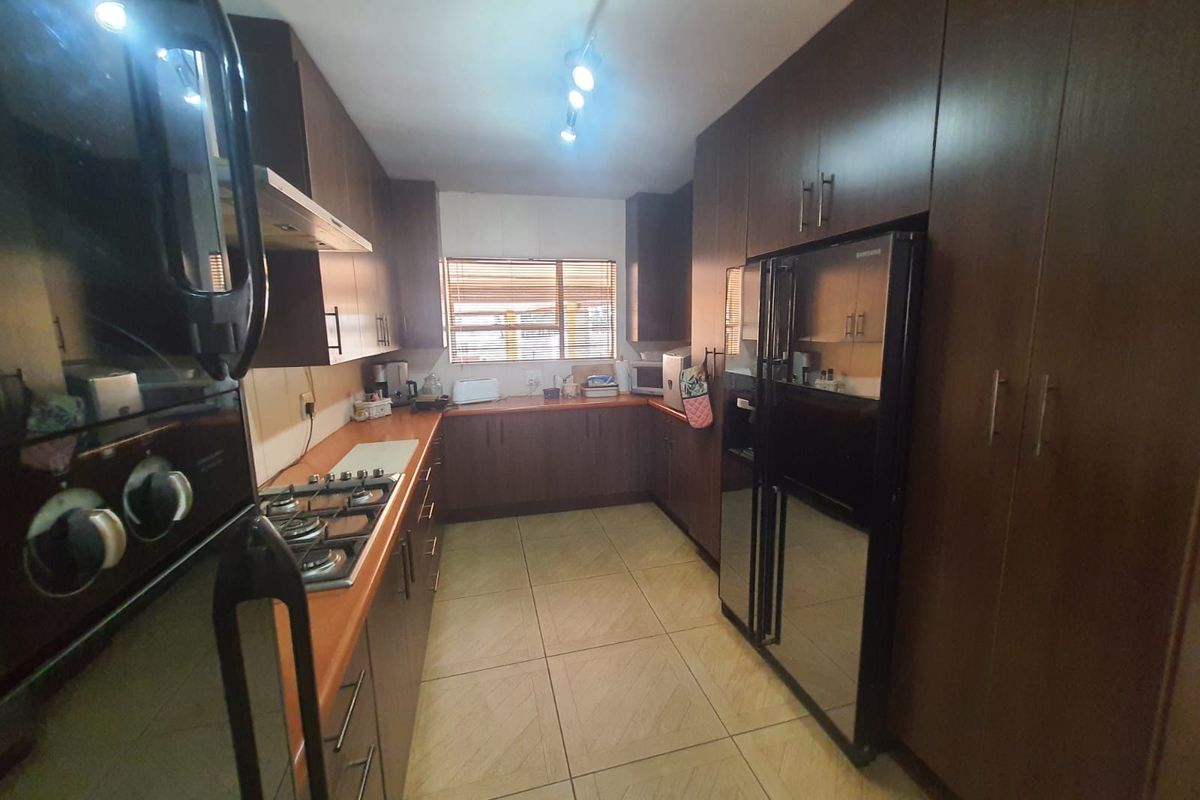 A functional galley-style kitchen featuring dark wood cabinetry, tiled flooring, a built-in gas hob, and an integrated oven.