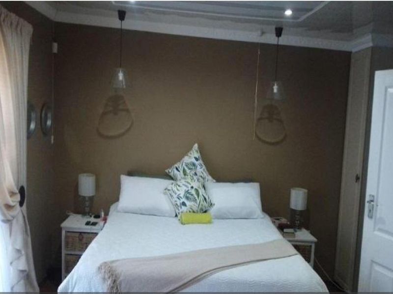 A cozy bedroom featuring neutral wall tones, built-in cabinetry, and modern pendant lighting, creating a comfortable and functional sleeping space.