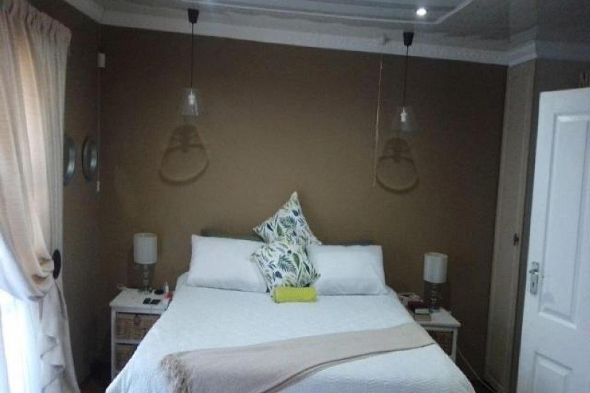 A cozy bedroom featuring neutral wall tones, built-in cabinetry, and modern pendant lighting, creating a comfortable and functional sleeping space.